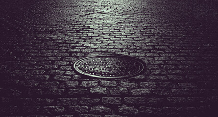 Manhole cover in an old cobblestone street in New York City creates dark and gritty textured background - 580406990
