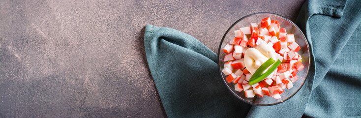 Delicious vegetarian salad of crab sticks, eggs, onion and corn in a bowl web banner. Top view © elenarui