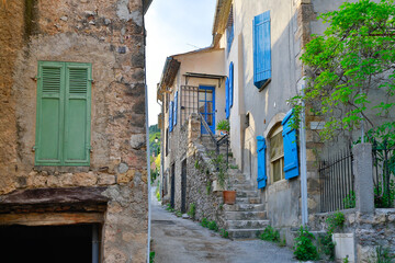 Idyllic french small city narrow streets with bright blue window shutters, stone buildings and rock pavement roads