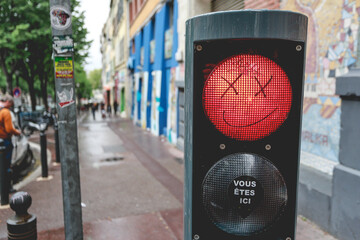 Smiley face drawing on red traffic light with crosses for eyes. Graffiti on traffic light with...