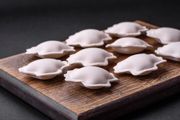 Raw frozen stuffed dumplings on a wooden cutting board