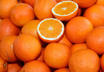 background of ripe orange oranges and some cut in half for sale in the greengrocer