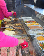 Cooks that cook street food with meat and vegetables in the hot metal plate at the fair