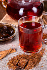 Infuser with dry rooibos leaves on grey wooden table, closeup