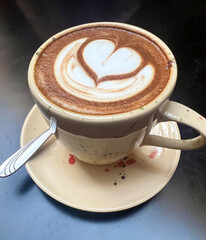 Cup of coffee with heart shape on black background. Top view with copy space. Cappuccino with foam in the form of heart. The concept of love for coffee. Close up Coffee latte art on black background