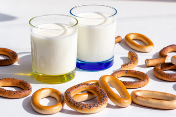 Fresh milk in glasses and bagels with poppy seeds on a table.