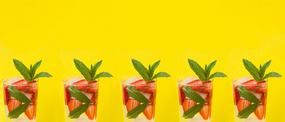 Summer drink. Lemonade or infused water with strawberry and mint in the drinking glasses on the yellow  background. Close-up. Copy space.
