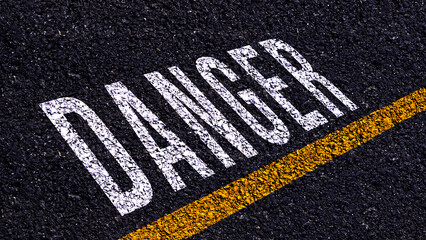 Danger written and yellow line on the road in middle of the asphalt road, Danger word on street.