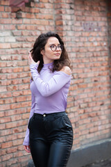 Beautiful young woman with brunette curly hair, portrait in eye glasses enjoying the sun in the city.