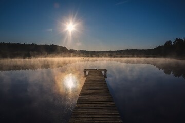 Beautiful summer morning landscape. Wooden pier on the lake shore in the misty morning scenery. Photo taken in Michala Gora, Poland.