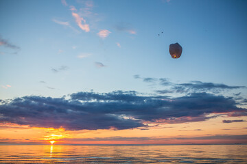 Sky lantern going up the air in from of beautiful sun set over the sea at beach