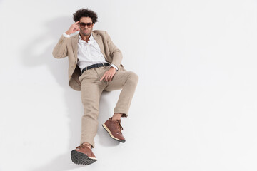 sexy man with curly hair laying down on the floor and pointing finger to temple