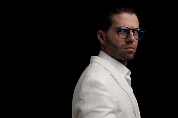 Obraz premium side view of cool elegant man with glasses wearing white suit