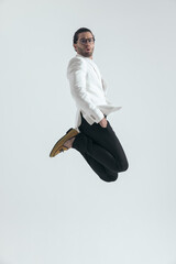 side view of cool man holding hands in pockets jumping in the air