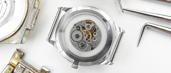 Broken watch and tools for repair on white background