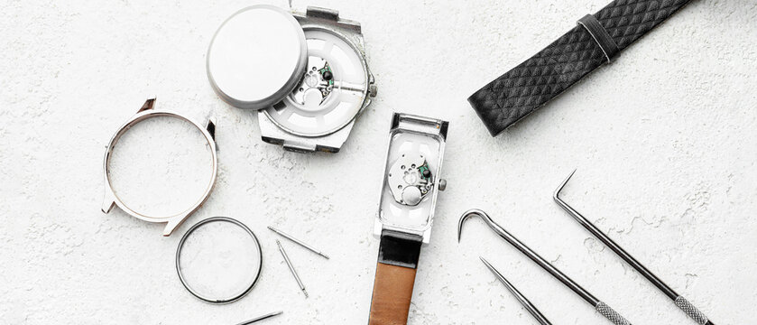 Broken watches and tools for repair on light background