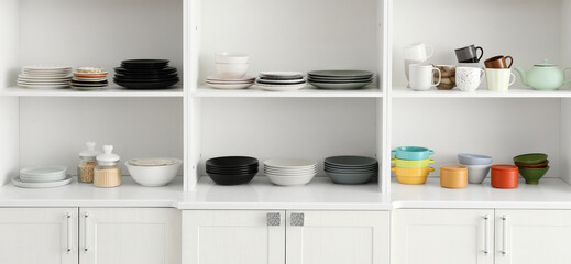 Open cupboard with clean dishes in kitchen