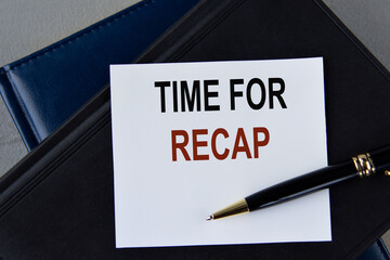 TIME FOR RECAP - words on white sheet on a black leather book with pen