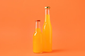 Bottles of tasty drinks on orange background