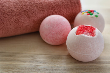 Different bath bombs on light wooden table, closeup