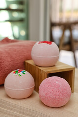 Different bath bombs on light wooden table in room