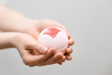 Woman with bath bomb on light background