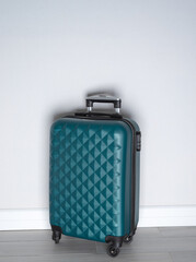 Green wheel suitcase in light room interior. Suitcase packed for travel. Ready for a trip.