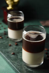Board with glasses of tasty Cafe Bombon on color background