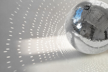 A mirror ball with sunbeams on a photo studio cyclorama. Natural light with shadows. Space for...