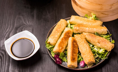Fried spring rolls on a dark stone plate