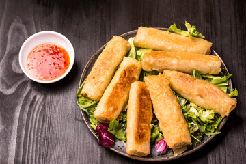 Fried spring rolls on a dark stone plate