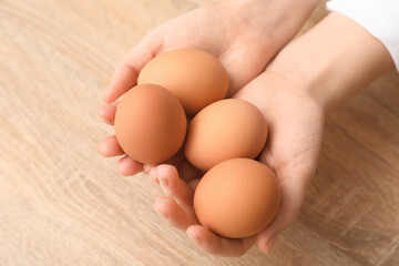 Woman with boiled egg on wooden table, closeup