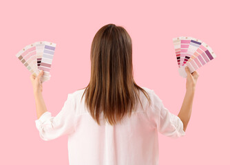 Beautiful woman with paint color palettes on pink background, back view