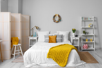 Interior of light bedroom with Easter wreath and tulips in vase