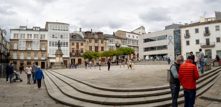 Plaza Mayor de Viveiro en Lugo, con gente paseando, dia nublado y edificios con árboles verdes y escaleras en primer plano. Galicia, España, verano 2021