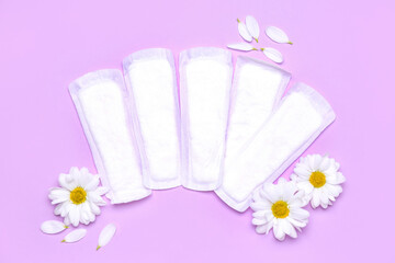 Composition with menstrual pads and chamomile flowers on lilac background