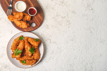 Plate with tasty nuggets and sauces on light background