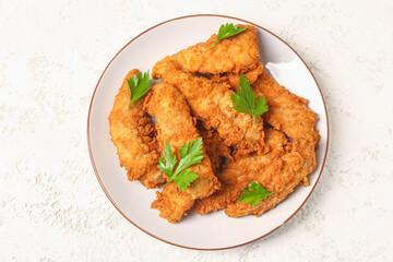 Plate of tasty nuggets with parsley on light background