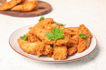 Plate of tasty nuggets with parsley on light background