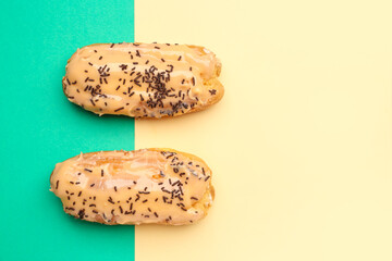 Tasty glazed eclairs on yellow and turquoise background
