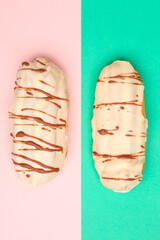 Tasty glazed eclairs on pink and turquoise background