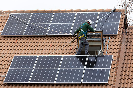 T&eacute;cnico instalando placas solares en un chalet.