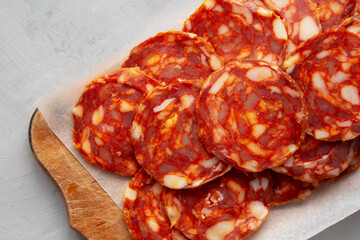 Spanish chorizo salami sausage on a rustic wooden board on a gray background, top view.