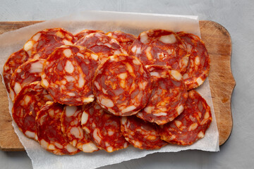 Spanish chorizo salami sausage on a rustic wooden board on a gray background, top view. Flat lay, overhead, from above.