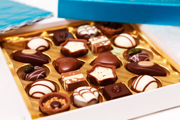 Close up of open small gift box of Swiss chocolate candies. Luxurious selection of milk, dark and white miniature masterpieces