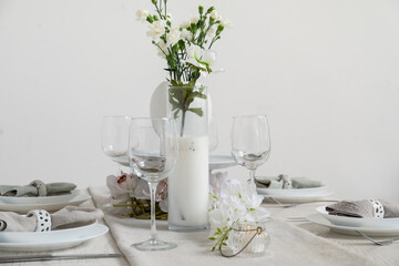 Beautiful table setting for International Women's Day celebration with eustoma and orchid flowers in light room