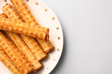 Plate of wafer rolls with boiled condensed milk on grey background, closeup