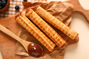 Delicious wafer rolls with boiled condensed milk on board, closeup