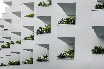 exterior of white residential apartment building with green plants on balconies. modern city architecture