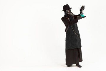Full-length portrait of a plague doctor from Medieval era holds a glass vessel containing a potion or serum, antidote. Isolated on a white background. epidemic and pandemic concept.